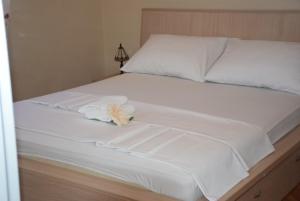 een bed met witte lakens en een knuffeldier erop bij Apartments Zelic in Vodice