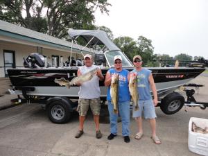 three people holding fish in front of a boat at Theater Motel in Westfield