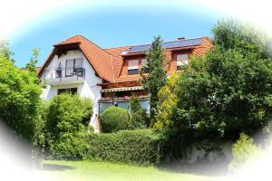ein Haus mit einem orangenen Dach und Bäumen und Sträuchern in der Unterkunft Pension Höchemer in Bad Bocklet