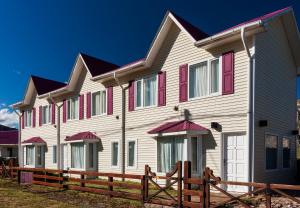 a large white house with red windows and a wooden fence at Lo de Tomy in El Chalten