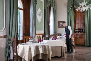 um homem de pé numa mesa numa sala de jantar em Hotel Ercolini & Savi em Montecatini Terme
