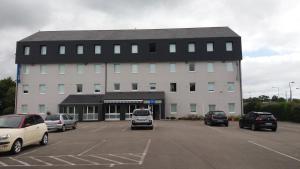 duży budynek z samochodami zaparkowanymi na parkingu w obiekcie ibis budget Concarneau w mieście Concarneau