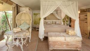 a bedroom with a canopy bed and a chair at Khwan Beach Resort - Luxury Glamping and Pool Villas Samui - Adults Only - SHA Extra Plus in Mae Nam
