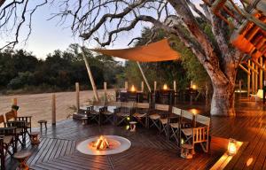 a wooden deck with a table and chairs and a tree at Rhino Post Safari Lodge in Skukuza