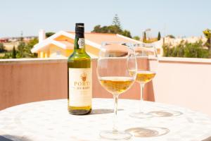 a bottle of wine and two wine glasses on a table at Grace Villa in Aldeia de Juso
