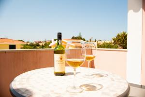 a bottle of wine and two glasses on a table at Grace Villa in Aldeia de Juso