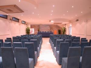 a large room with chairs and a stage in the background at Hotel De La Ville in Civitavecchia