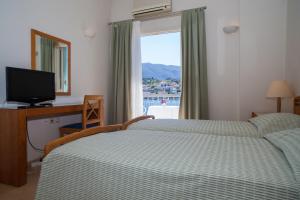 Schlafzimmer mit einem Bett, einem TV und einem Fenster in der Unterkunft Hotel Saron in Poros