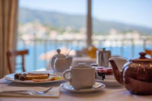 una mesa con un plato de comida y tazas de café en Hotel Saron en Poros