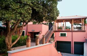 ein rosafarbenes Haus mit einer Treppe und einer Veranda in der Unterkunft ALHAMBRA - B&B - Guest House di Charme in Giarre