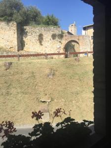 una vieja pared de piedra con una puerta en un campo en Appartamenti Il Criollo en San Gimignano