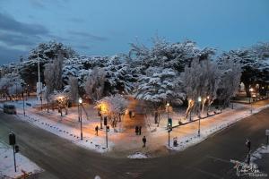 Hotel Plaza في بونتا أريناس: حديقة مغطاة بالثلج في الليل مع الناس يمشون