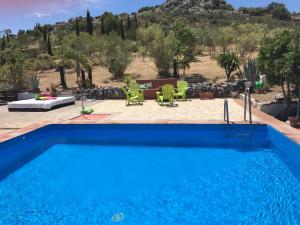 a blue swimming pool with a table and chairs at Cortijo Nuevo Alojamiento Rural in Cuevas del Becerro