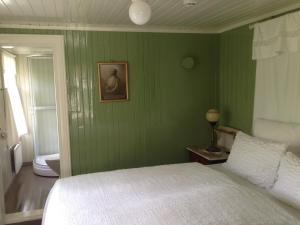 a green bedroom with a bed and a picture on the wall at Storjord Hotel in Storjord