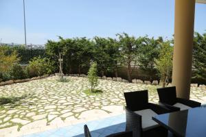 a stone patio with two tables and chairs and trees at Eden Village in Margherita di Savoia