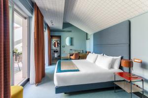 a bedroom with a large white bed and a living room at Room Mate Collection Giulia, Milan in Milan