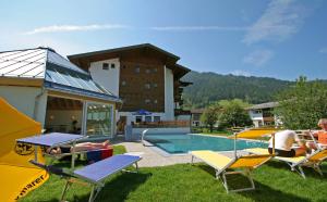 un grupo de personas sentadas en sillas junto a una piscina en Hotel Simmerlwirt, en Niederau