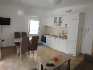 a kitchen with white cabinets and a table and a tableablish at Apartman Stijepčić in Herceg-Novi