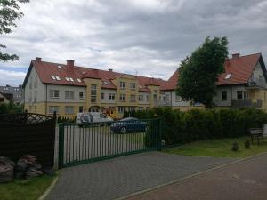 a fence in front of a house with a car at Apartament w Rezydencji Marino Rewal in Rewal