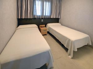 
a room with two beds and two windows at Apartamentos Marina d'Or Beach 2ª Linea in Oropesa del Mar
