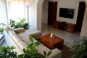 a living room with a white couch and a tv at Villa Relax Vendégház in Gárdony