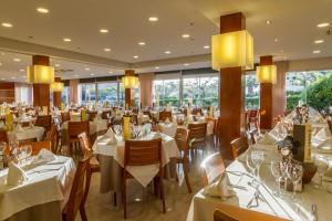 ein Restaurant mit weißen Tischen, Stühlen und Fenstern in der Unterkunft Hotel Panorama in L'Estartit