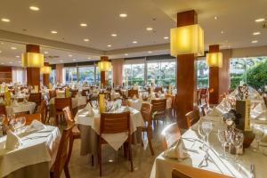 a restaurant with white tables and chairs and windows at Hotel Panorama in L'Estartit