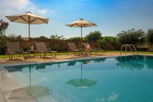 Almiros BeachにあるSkales Villasのパラソル2つと椅子2脚、テーブル、プールが備わるスイミングプールを併設しています。