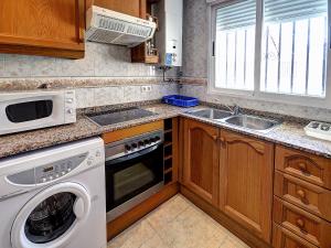 
a kitchen with a stove a sink and a microwave at Apartamentos Marina d'Or Beach 2ª Linea in Oropesa del Mar
