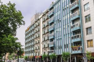 a tall building on a city street with trees at Apartamento do Parque in Espinho