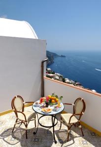 d'une table et de chaises sur un balcon avec vue sur l'océan. dans l'établissement Locanda Degli Dei, à Praiano