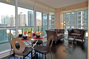 a living room with a table and chairs and windows at Royal Stays Furnished Apartments - Square One in Mississauga