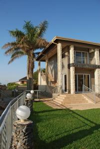 a house with a palm tree in front of it at Umthunzi Hotel and Conference in Umtentweni