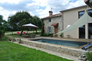 a house with a swimming pool and an umbrella at les epis du vent in Adilly