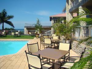 un patio con tavoli e sedie accanto alla piscina di Umthunzi Hotel and Conference a Umtentweni