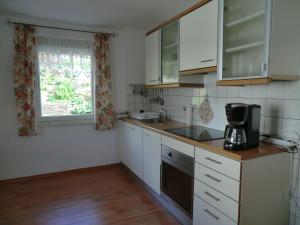 uma cozinha com armários brancos, um lavatório e uma janela em Ferienwohnung Kehmeier em Polle