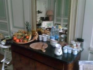 a table with a bowl of fruit and a mirror at Le Chateau De La Vierge in Bures-sur-Yvette