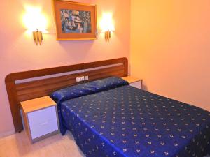 a bedroom with a bed with a blue comforter at Hostal Bonavista in Calella