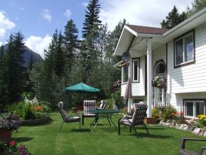 un patio con sillas, una mesa y una sombrilla en Silvern Lake Trail Bed and Breakfast, en Smithers