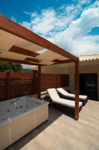 a deck with a bath tub and a bed on a patio at Riviera Perdika Hotel in Perdika