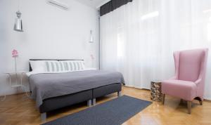 a bedroom with a bed and a pink chair at Dóm Apartman in Szeged