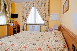 um quarto com uma cama, uma secretária e uma janela em Hotel Agata em Biella