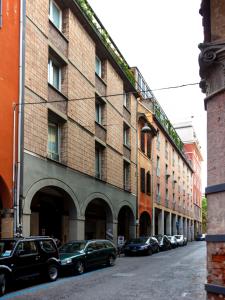 un gran edificio de ladrillo con coches aparcados en una calle en Appartamenti Astoria en Bolonia
