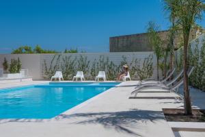 a woman sitting in a chair next to a swimming pool at Calura Residence in Carpignano Salentino