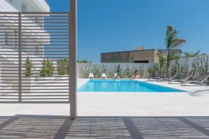 a swimming pool with chairs next to a building at Calura Residence in Carpignano Salentino