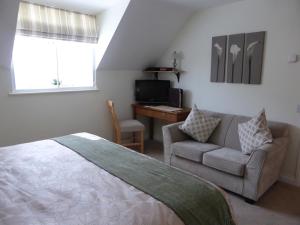 a bedroom with a bed and a couch and a desk at Liongate House in Ilchester
