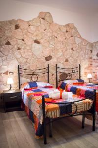 2 Betten in einem Zimmer mit einer Steinmauer in der Unterkunft Rocca Pinta Guest House in Alghero