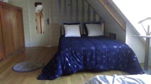 Bett mit blauer Decke in einem Zimmer in der Unterkunft Chambre d'Hotes Les Hortensias in Rang-du-Fliers