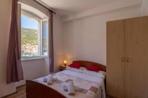 a bedroom with a bed with red pillows and a window at Apartment Riva 5 in Komiža