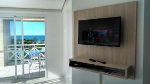 sala de estar con TV de pantalla plana en la pared en Brava Apart Hotel, en Florianópolis